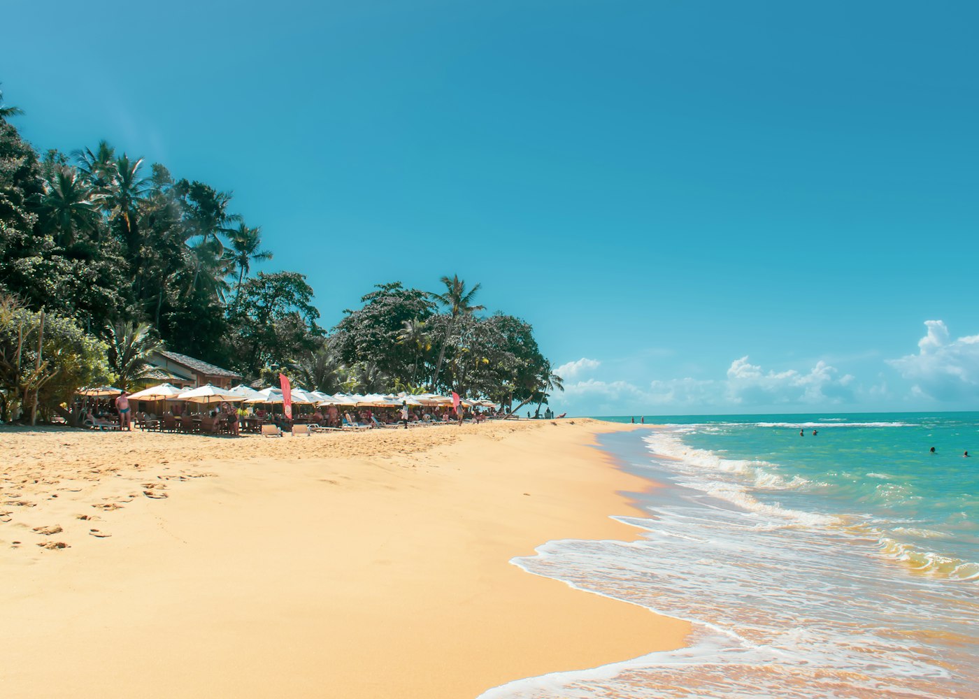 Praia de areia dourada com coqueiros e mar azul na região de Porto Seguro
